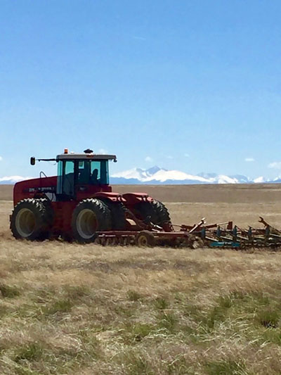 tractor in field with mountains behind